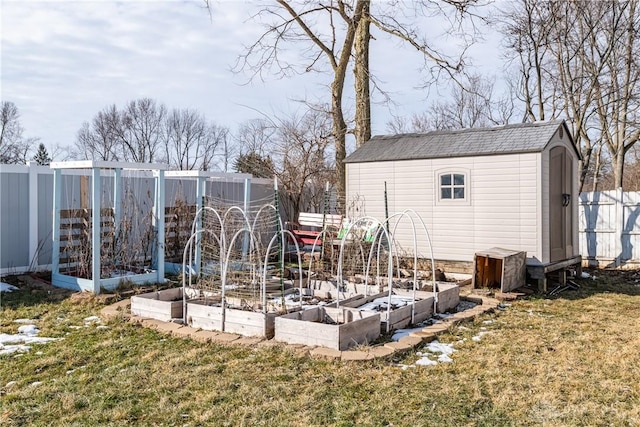 view of yard featuring a shed, fence, a vegetable garden, and an outbuilding