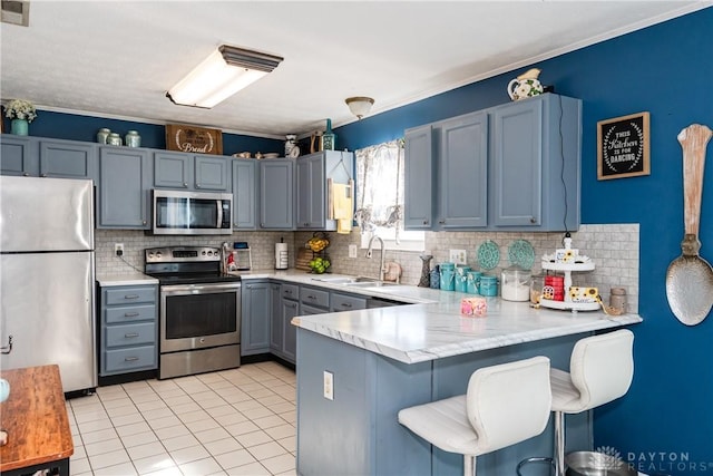 kitchen with stainless steel appliances, a peninsula, a sink, and light countertops