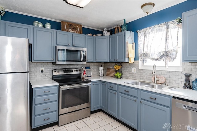 kitchen with light countertops, appliances with stainless steel finishes, a sink, and blue cabinets