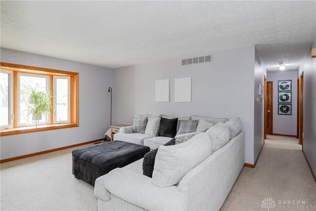 living area featuring baseboards, a textured ceiling, visible vents, and light colored carpet