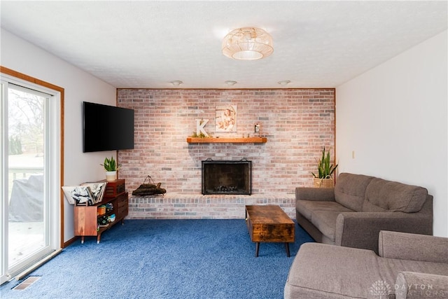 carpeted living area with a brick fireplace, brick wall, visible vents, and a textured ceiling