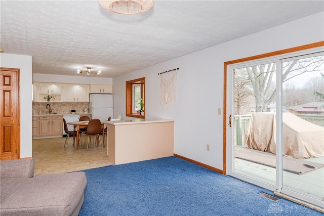 living room featuring visible vents, plenty of natural light, a textured ceiling, and baseboards