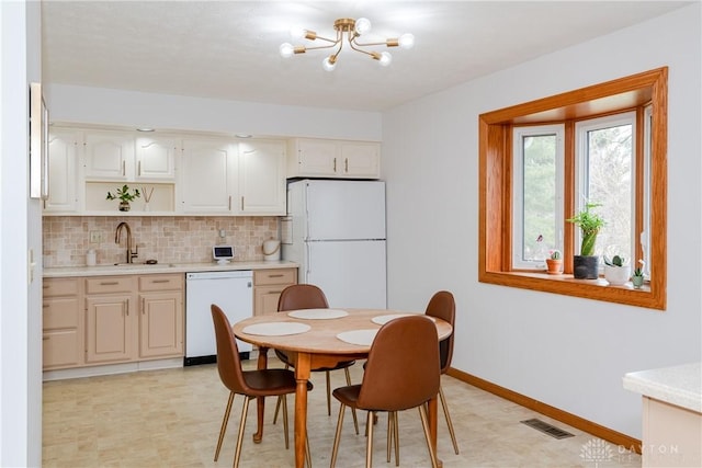 kitchen featuring white appliances, visible vents, light countertops, and a sink