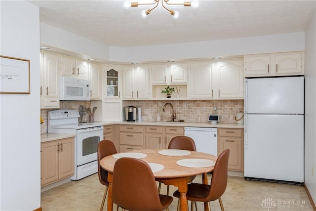 kitchen featuring white appliances, decorative backsplash, glass insert cabinets, light countertops, and a sink