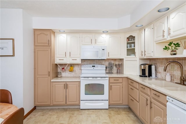 kitchen featuring white appliances, backsplash, light countertops, and a sink