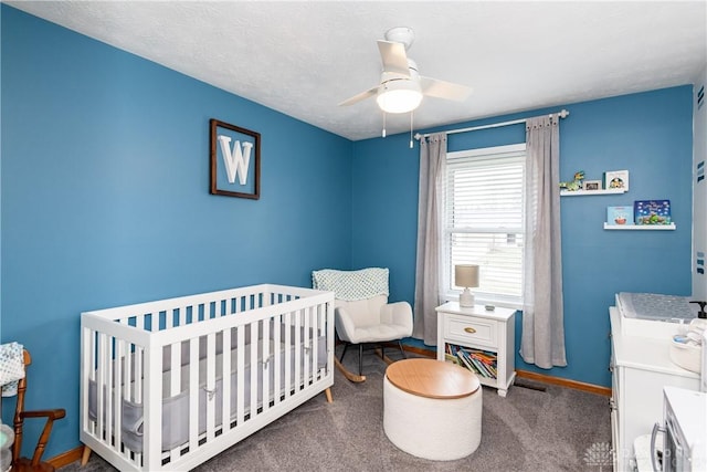 bedroom featuring ceiling fan, a textured ceiling, carpet floors, baseboards, and a crib