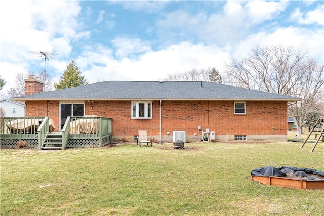 rear view of house with brick siding, a yard, a chimney, and a wooden deck