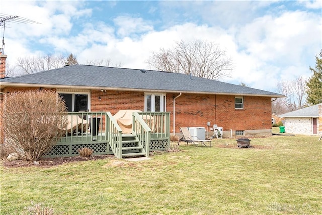 rear view of property with brick siding, a chimney, a lawn, an outdoor fire pit, and a deck