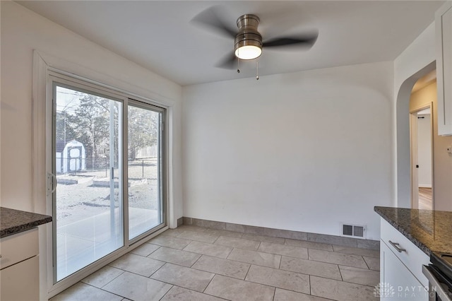 unfurnished dining area featuring a ceiling fan, arched walkways, and visible vents