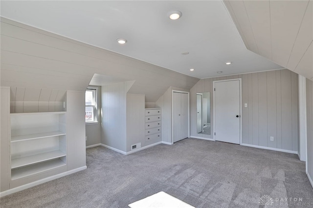 additional living space featuring built in shelves, lofted ceiling, visible vents, carpet flooring, and baseboards