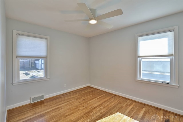 empty room featuring light wood-style floors, visible vents, ceiling fan, and baseboards