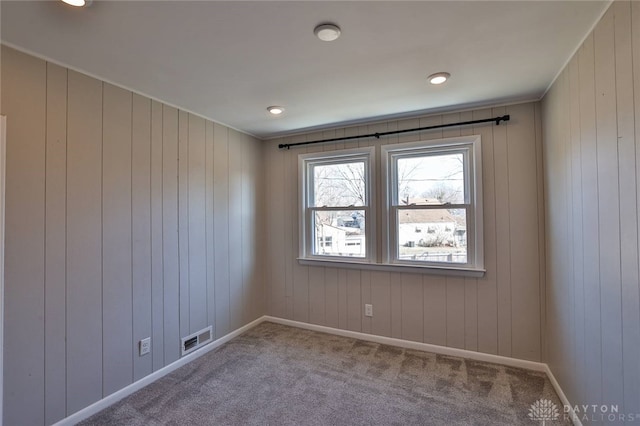 carpeted spare room with visible vents and baseboards