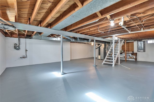 unfinished basement featuring stairway, electric panel, and heating unit