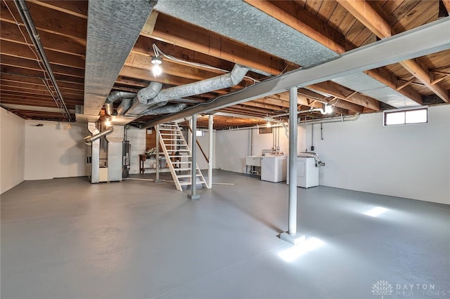 below grade area featuring washing machine and clothes dryer, heating unit, stairs, water heater, and a sink