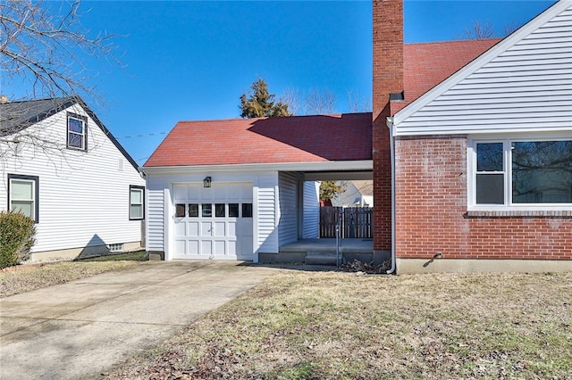 view of side of home featuring an attached garage, brick siding, a yard, driveway, and a chimney