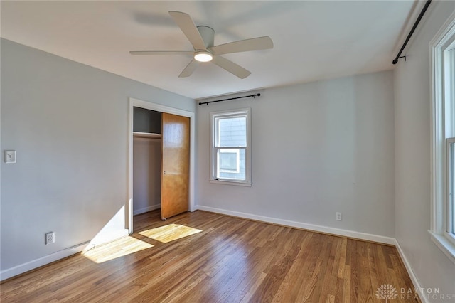 unfurnished bedroom featuring a closet, wood finished floors, a ceiling fan, and baseboards