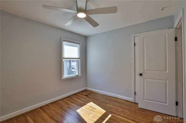 spare room featuring a ceiling fan, baseboards, and wood finished floors