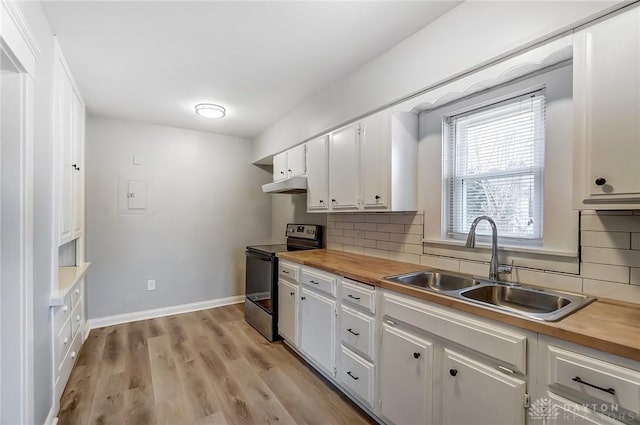 kitchen with electric stove, butcher block counters, a sink, and under cabinet range hood