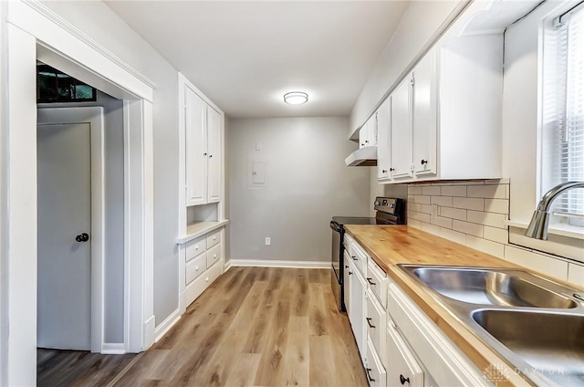 kitchen featuring butcher block counters, white cabinets, a sink, and stainless steel electric range