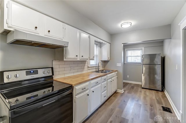 kitchen featuring range with electric cooktop, freestanding refrigerator, a sink, under cabinet range hood, and backsplash