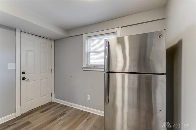 kitchen featuring freestanding refrigerator, white cabinets, baseboards, and light wood finished floors