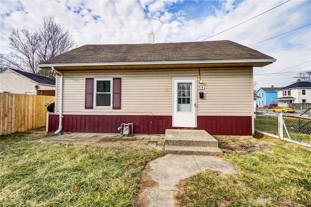 bungalow-style house with roof with shingles, fence, and a front lawn