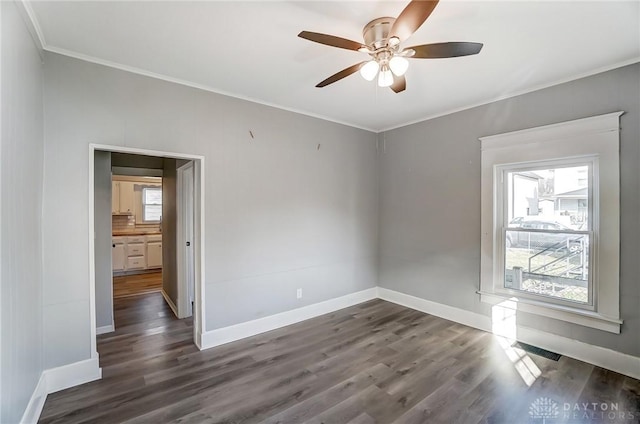 spare room with crown molding, dark wood finished floors, visible vents, ceiling fan, and baseboards