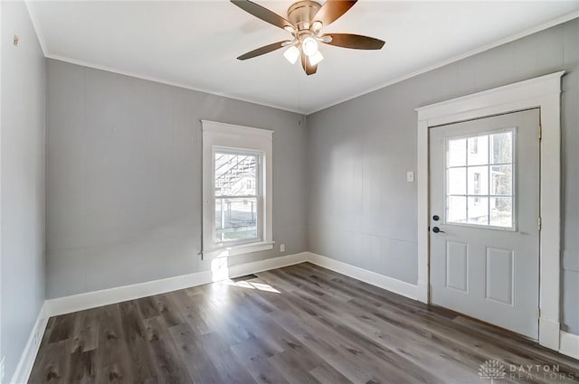 interior space with crown molding, wood finished floors, a ceiling fan, and baseboards