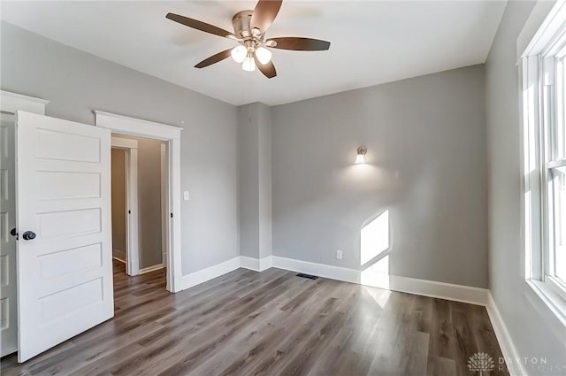 unfurnished room featuring a ceiling fan, visible vents, baseboards, and wood finished floors