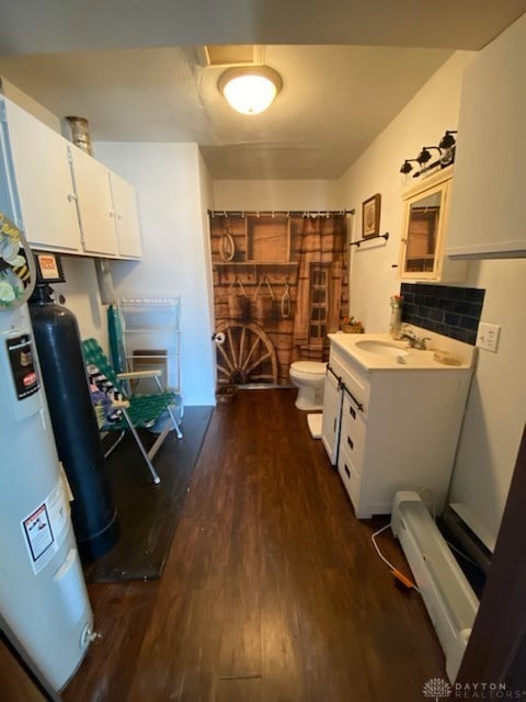 bathroom with toilet, wood finished floors, vanity, water heater, and backsplash