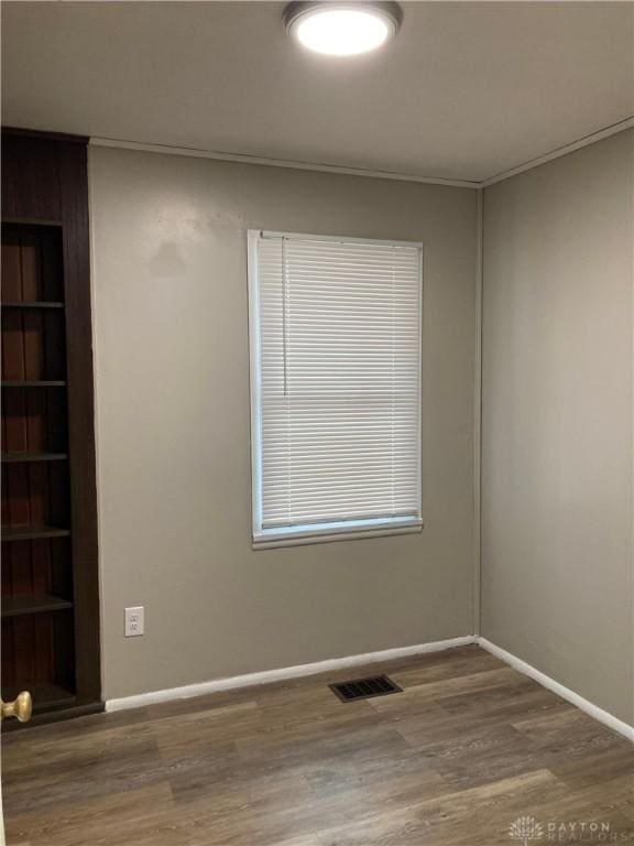 unfurnished room with visible vents, baseboards, and wood finished floors