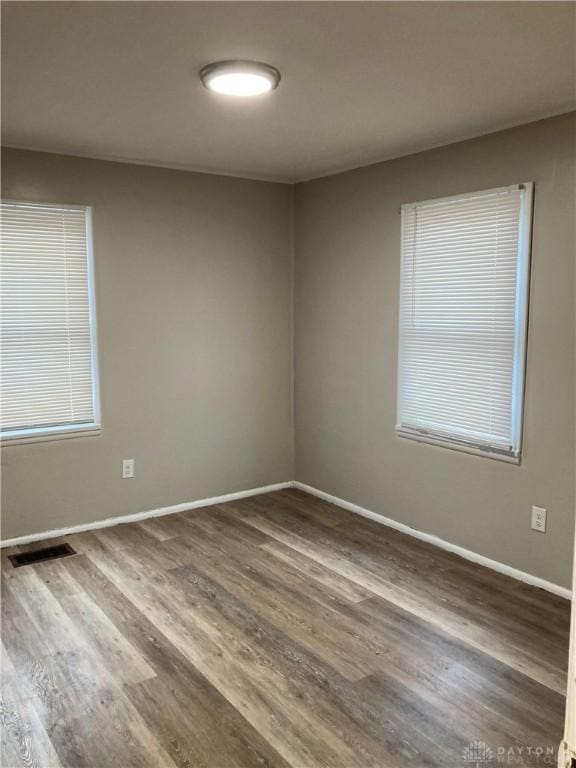 empty room featuring visible vents, baseboards, and wood finished floors