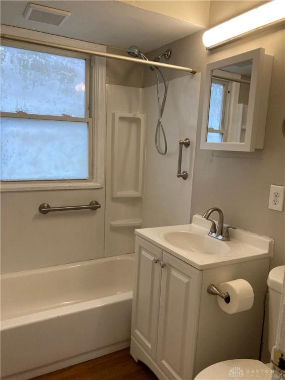 bathroom with toilet, wood finished floors, visible vents, bathing tub / shower combination, and vanity