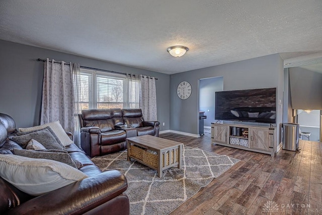 living room with a textured ceiling, baseboards, and wood finished floors