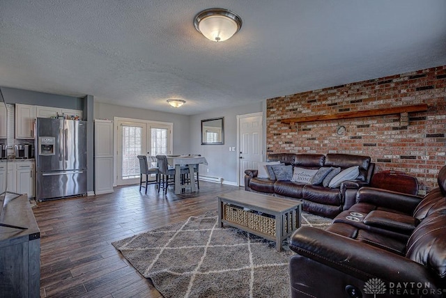 living room with a baseboard radiator, dark wood-type flooring, a textured ceiling, brick wall, and baseboards