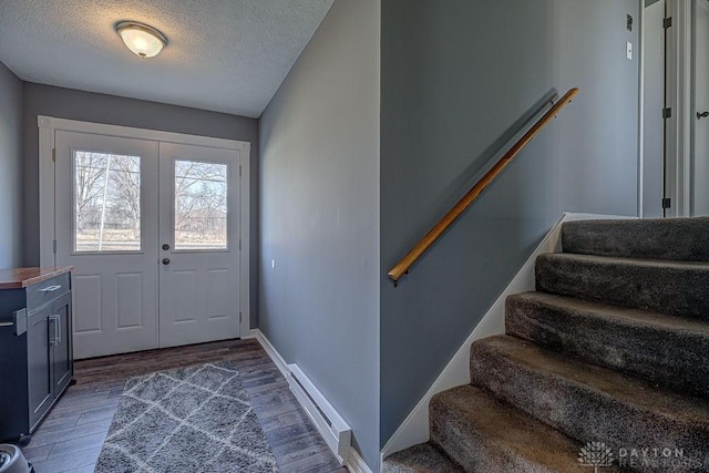 foyer entrance featuring a baseboard heating unit, french doors, stairway, and wood finished floors