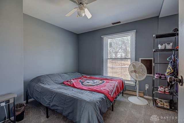 carpeted bedroom featuring a baseboard heating unit and a ceiling fan