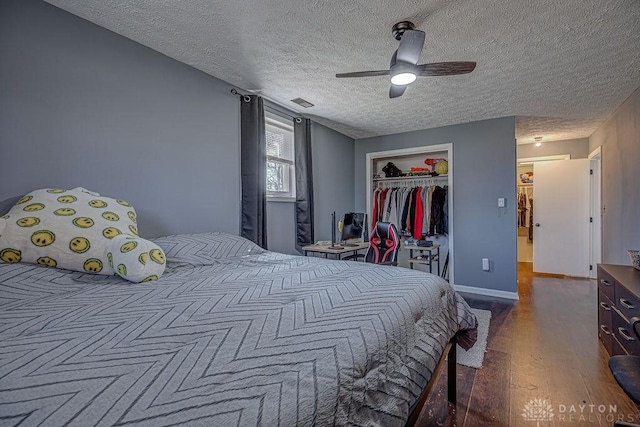 bedroom featuring a closet, ceiling fan, a textured ceiling, wood finished floors, and baseboards