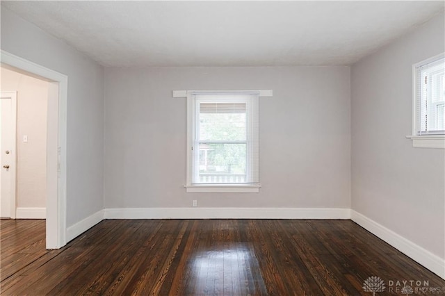 unfurnished room with dark wood finished floors and baseboards