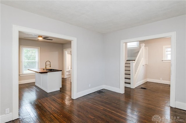 spare room with dark wood finished floors, visible vents, stairway, a sink, and baseboards