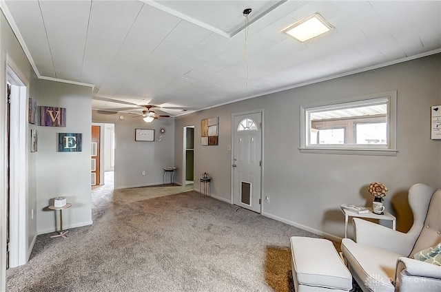 carpeted entrance foyer with a ceiling fan, crown molding, and baseboards