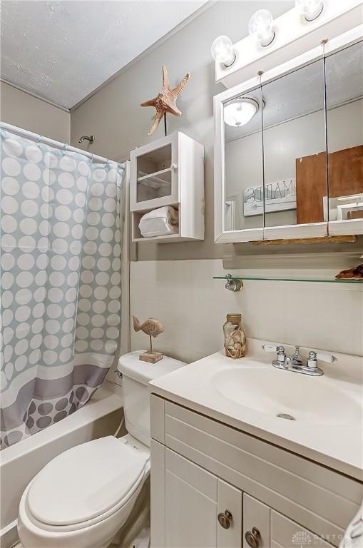 bathroom with toilet, shower / bath combination with curtain, and vanity