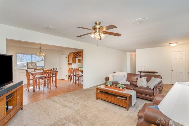 living room featuring ceiling fan with notable chandelier and light colored carpet