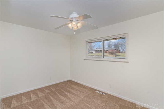 carpeted spare room featuring ceiling fan, visible vents, and baseboards