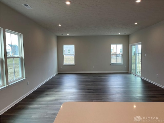 spare room with baseboards, a textured ceiling, dark wood finished floors, and recessed lighting