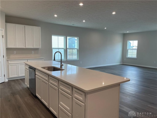 kitchen with white cabinets, an island with sink, dishwashing machine, light countertops, and a sink