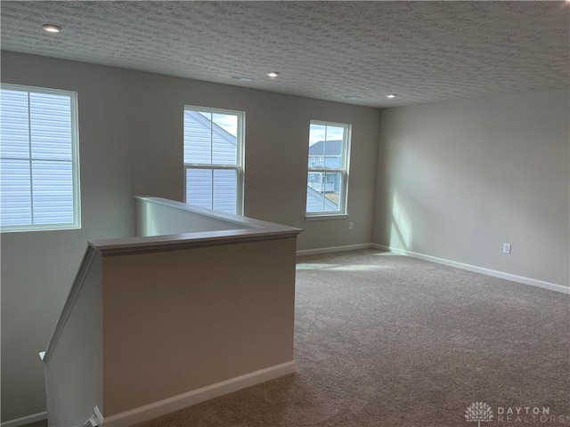 empty room featuring a textured ceiling, baseboards, and carpet flooring