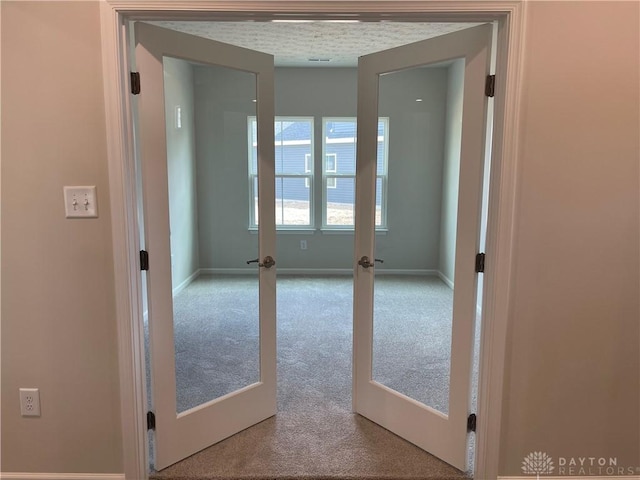 corridor with french doors, carpet flooring, and baseboards