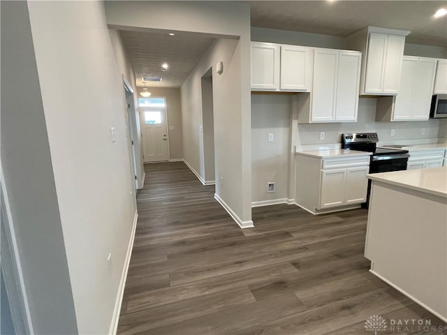 kitchen featuring dark wood-style floors, light countertops, appliances with stainless steel finishes, white cabinetry, and baseboards