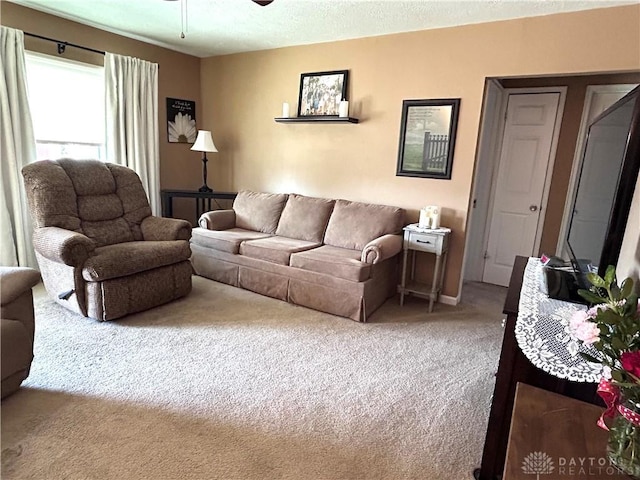 living room with carpet, ceiling fan, and a textured ceiling